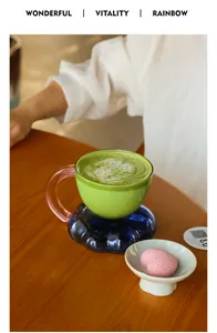 Detailed view of a unique cloud-shaped base glass mug with matcha latte in a cafe.
