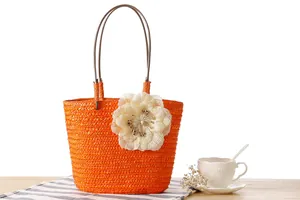 Vibrant orange straw woven tote bag with a decorative large cream mesh flower