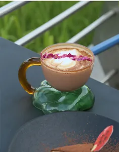 Detail view of floating cloud glass coffee mug with latte art and dried rose petals