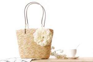 Elegant hand-woven straw beach bag featuring a large decorative flower detail on table