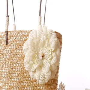 Close-up of decorative cream flower detail on a straw woven summer beach tote