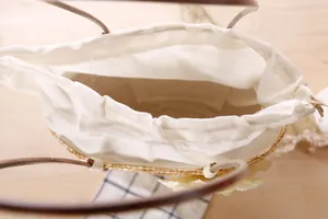 Detailed interior view of a woven straw beach bag showing its cream drawstring lining