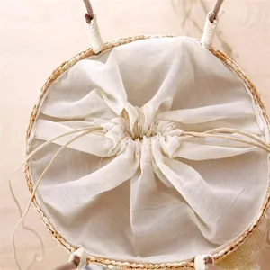 Detailed macro view of a natural straw woven beach bag featuring its cream linen drawstring.