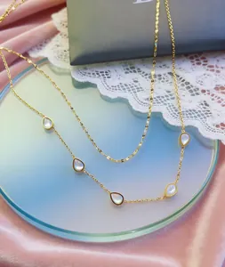 Detailed view of gold titanium steel double necklace featuring white mother-of-pearl teardrops