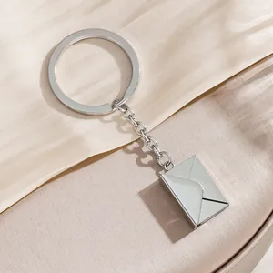 Creative silver envelope keychain with glossy metallic finish on elegant silk background