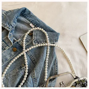 Close-up view of elegant pearl strap and metallic kiss lock on a Chinese style embroidered bag