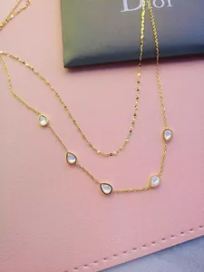 Detailed close-up view of a gold double-layer necklace with teardrop mother-of-pearl pendants.
