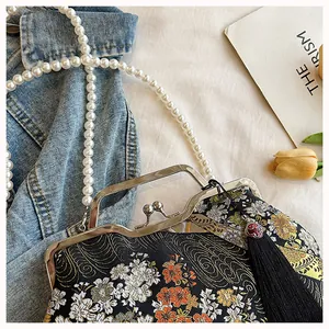 Close-up of Neo-Chinese embroidered bag featuring pearl chain and tassel detail.
