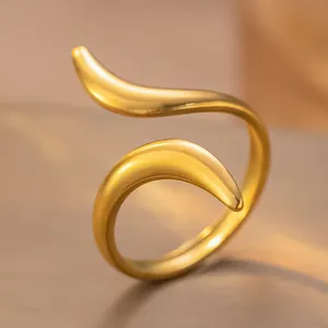 Vue détaillée d'une bague ouverte dorée aux formes ondulées irrégulières et fini poli