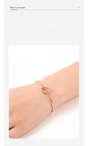 Macro view of a minimalist rose gold heart-shaped stainless steel open bangle worn on the wrist