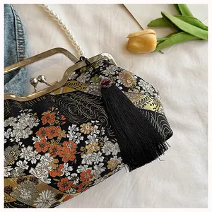 Detailed view of Chinese style embroidered handbag with metal kiss-lock and silk tassel