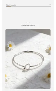 Close-up detail of a minimalist silver-tone stainless steel open heart-shaped bangle