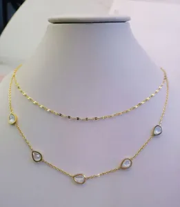Detailed view of a double-layered gold titanium steel necklace with mother of pearl charms