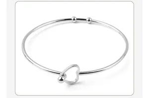 A detailed view of a minimalist silver stainless steel heart-shaped open bangle