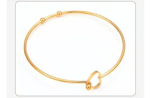 Close-up detail of a minimalist golden stainless steel bangle with heart-shaped closure
