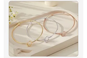 Detail view of minimalist stainless steel heart-shaped open bangles in three colors.