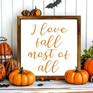 Macro view of wooden frame with 'I love fall most of all' text and pumpkin decor