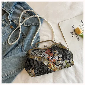 Detail showing intricate floral embroidery and pearl chain on a Chinese-style clutch.