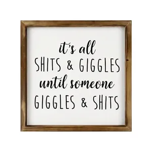Close-up of square wooden framed wall sign featuring humorous shits and giggles text
