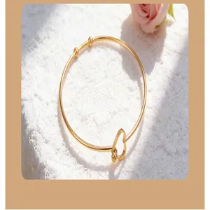 Detailed macro view of a gold heart-shaped stainless steel open bracelet on lace