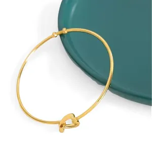 Elegant gold stainless steel open bangle bracelet featuring a minimalist heart-shaped knot.