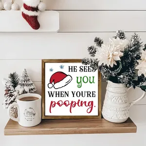 Humorous Christmas wooden frame sign with Santa hat illustration on a wooden shelf