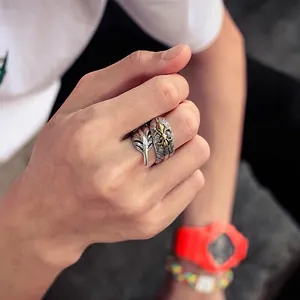 Close-up view of vintage Thai silver feather ring with gold emblem on a model hand.