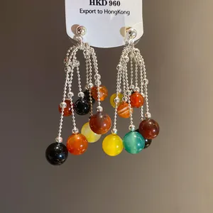 Macro dettaglio di orecchini a cascata retrò con vivaci perline multicolore.