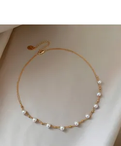 Detail of 18k gold plated necklace featuring elegant white pearl beads on a silk background