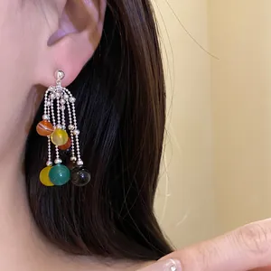 Primo piano di orecchini a nappa a cascata multicolori indossati sull'orecchio di modella.