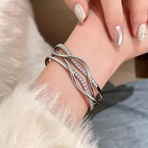 Detailed view of an 18k gold plated multi-layer crossover bangle with sparkling rhinestones