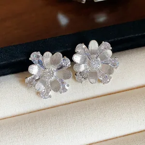 Detailaufnahme eleganter Blumenohrstecker mit Zirkonia und silbernen Blütenblättern