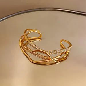 Close-up of 18k gold-plated multi-layer cuff bracelet with sparkling stones detail.