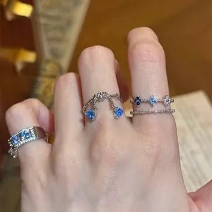 Close-up view of elegant blue zircon rings with triangle and floral designs on hand