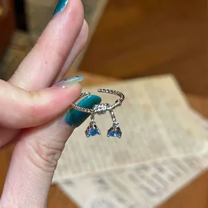 Macro detail view of a silver ring featuring two dangling blue triangle zircons