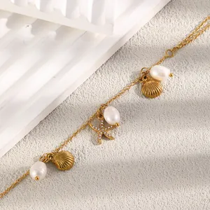 Exquisites Detail einer 18K vergoldeten Fußkette mit Seesternen, Muscheln und Perlen.
