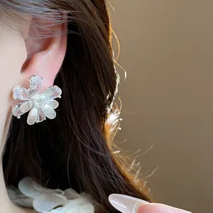 Nahaufnahme eines glitzernden Zirkonia-Blumenohrsteckers, der am Ohr getragen wird