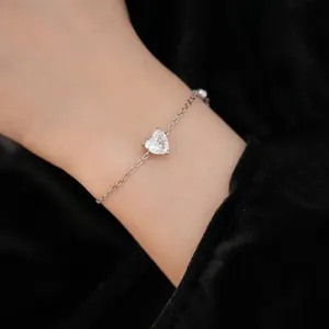 Close-up of a delicate silver bracelet featuring a sparkling heart-shaped zircon stone