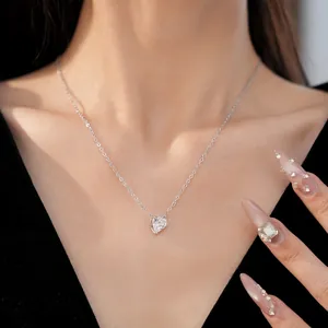 Close-up detail of a minimalist silver heart-shaped zircon pendant necklace worn on neck