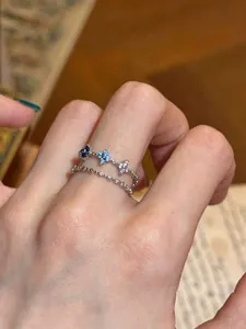 Detailed macro shot of a double-layered silver ring with blue and clear zircon flower motifs