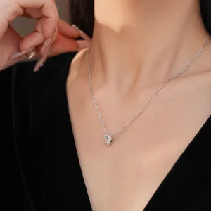 Detail shot of a minimalist silver heart necklace with a sparkling cubic zirconia pendant.