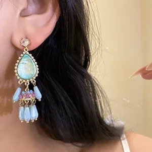 Close-up of retro palace style teardrop tassel earrings with vibrant blue crystals
