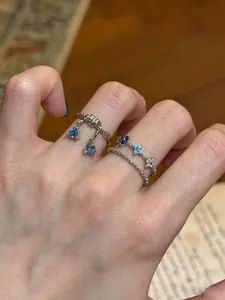 Detailed view of silver-tone rings with blue triangle charms and star-shaped zircon stones.