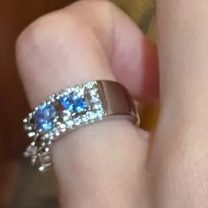 Macro shot of a minimalist silver ring with blue triangle zircons on a finger