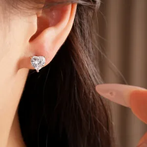 Detailed close-up showing a shiny heart-shaped zircon stud earring on a model's ear