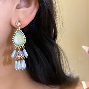 Close-up of vintage court style teardrop tassel earrings with crystals on an ear.