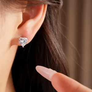 Detailed close-up of a elegant heart-shaped zircon stud earring worn on an ear model
