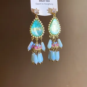 Close-up of vintage palace style teardrop tassel earrings with blue and pink beads.