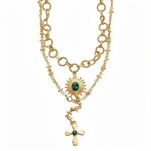 Vintage gold layered necklace featuring cross and sunburst emerald-green stone pendants