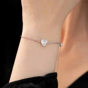 Close-up of minimalist silver bracelet featuring a sparkling zircon heart gemstone